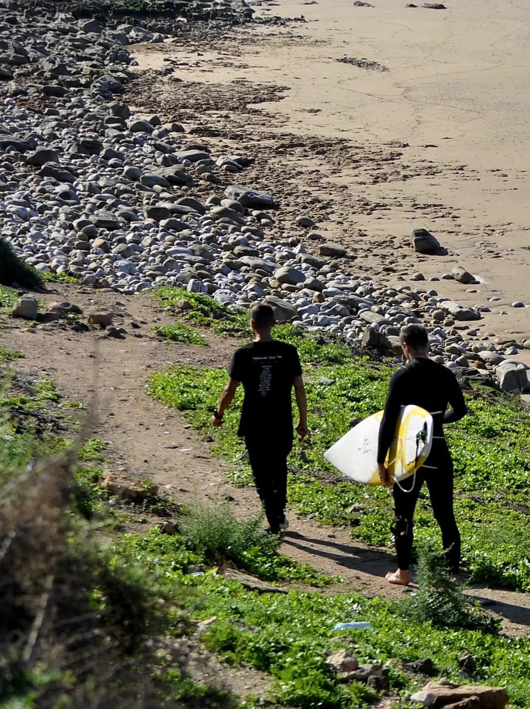Surfer carrying a board toward the beach in Taghazout