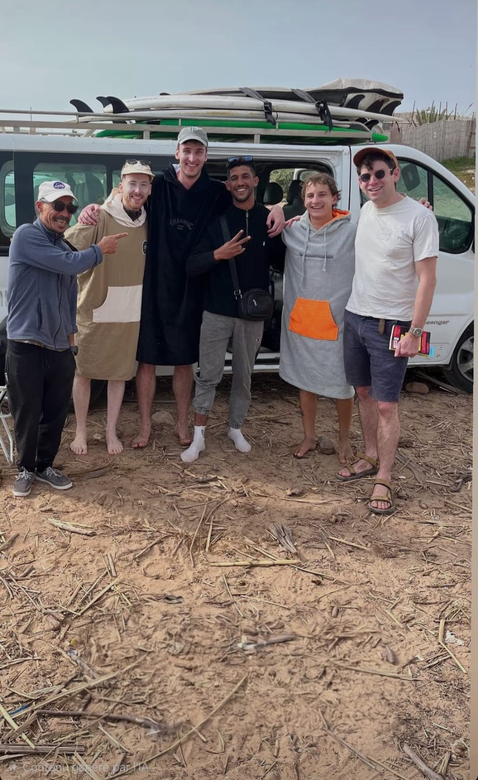 Surf guests standing together beside a van with boards on the roof